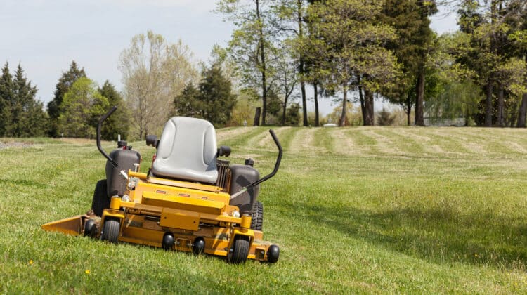 No person on expansive lawn with a yellow zero-turn mower