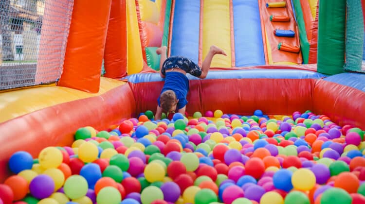 Smiling child girl jumping on inflatable ball in colorful colored castle