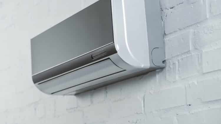 Close up shot of grey air conditioner hanging on white brick wall Air conditioning system for cool weather and blowing