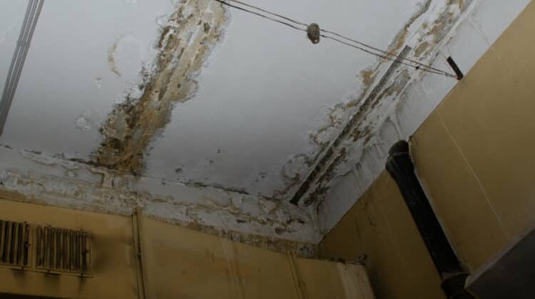 Big wet spots and cracks on the ceiling of the domestic house room after heavy rain and lot of water
