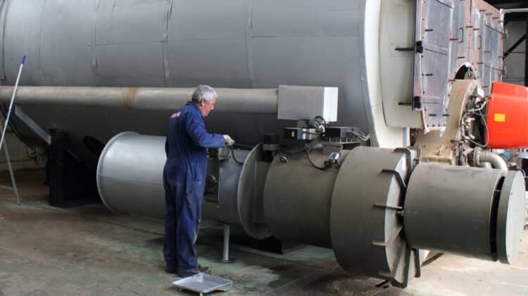An engineer painting an industrial steam boiler