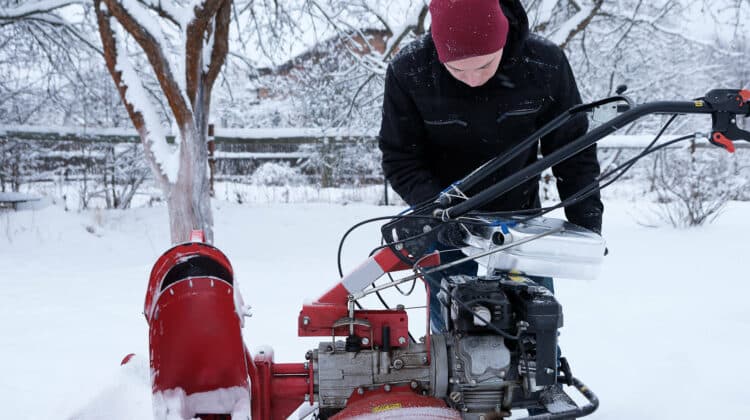 man pours gasoline into snow blower