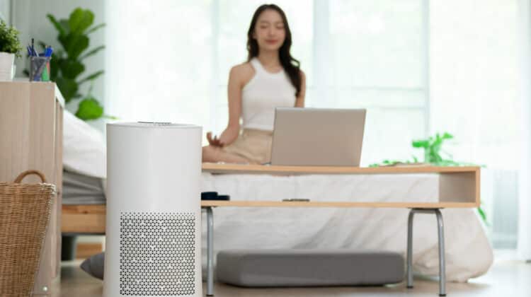 Woman doing yoga in the living room at home using air purifier equipment