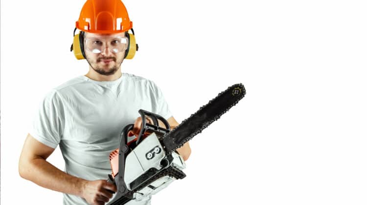 Bearded man in helmet hold chainsaw on blue background