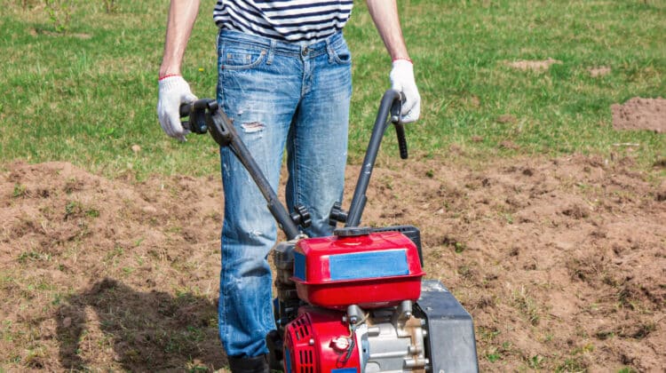 Man using tractor for working in field Tiller tool for loosening soil Gardening and cultivating plants