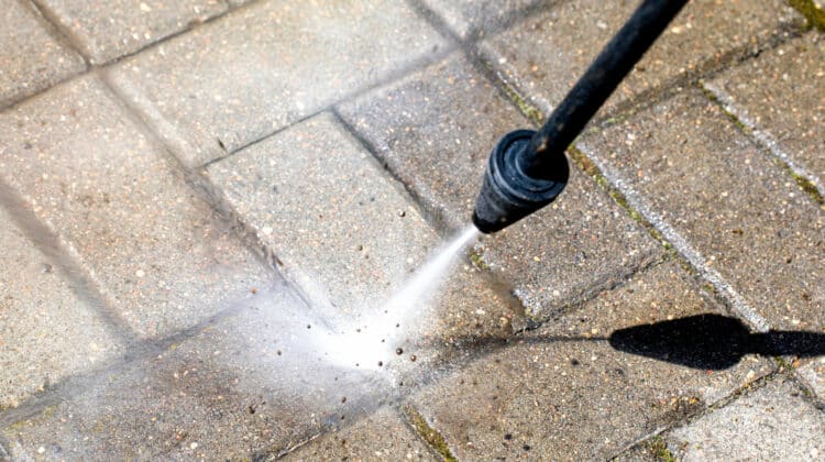 high-pressure washer cleans concrete stones of garden line in country house