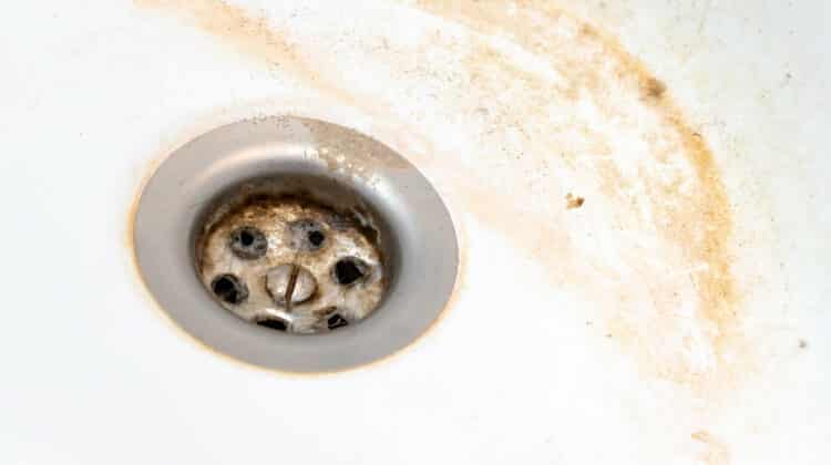 Closeup of limescale plumber filling out dirt hole in bathroom sink with washbowl