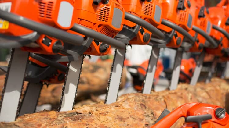 New Chainsaw machines over heap of firewood outdoor