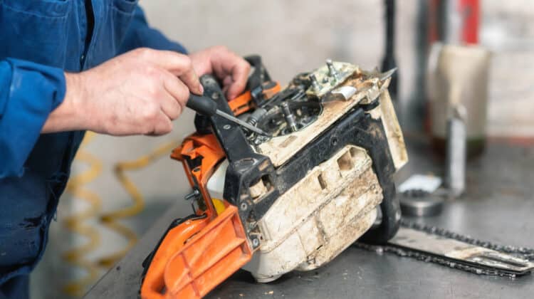 Mechanic repairing a chainsaw Man repairing a chainsaw in workbench