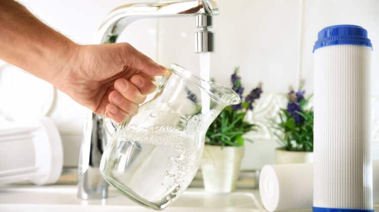 Hand filling jug from a tap with filtered osmosis water