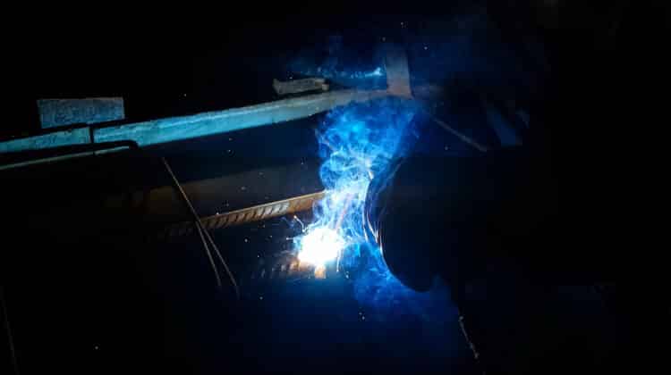 Man welds metal with sparks and light
