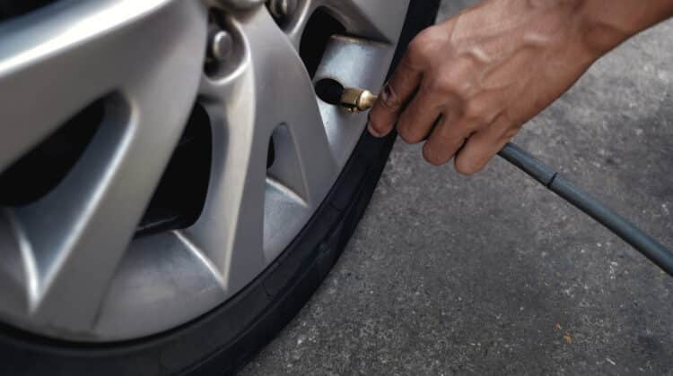 Male worker checking pressure of car tire at car filling station