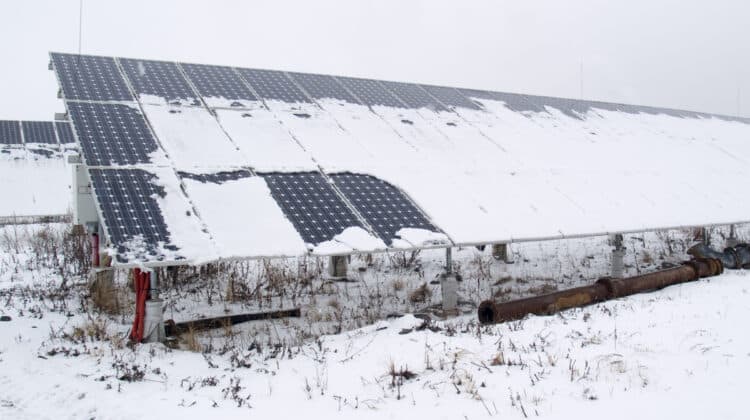 Rows of snow covered solar panels in small solar power plant