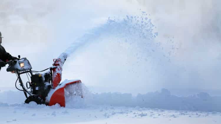 man working with snow blower after winter storm in city