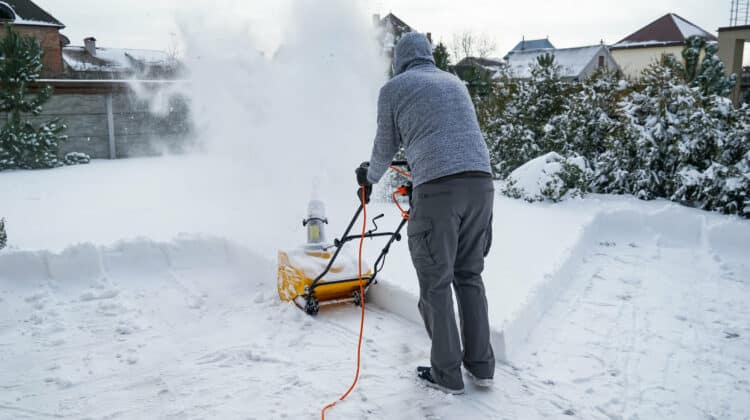 Man with machine removing snow in yard