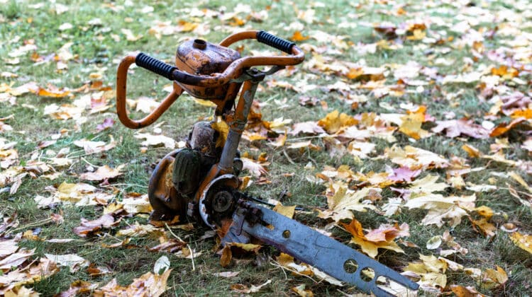 Old rusty chainsaw with broken metal and grass