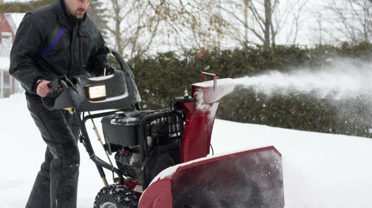 man operating snow blower in winter