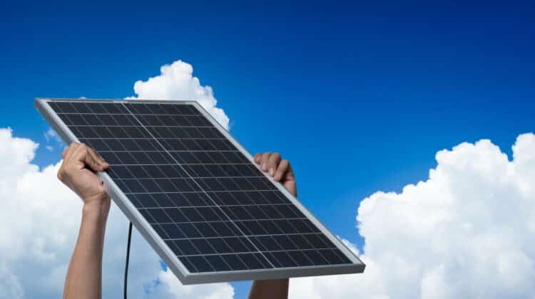 Hand holding a solar panel on blue sky background