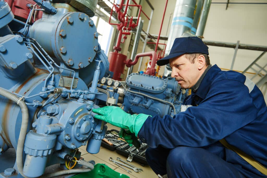 service engineer worker at industrial compressor refrigeration station repairing and adjusting equipment at manufacturing factory