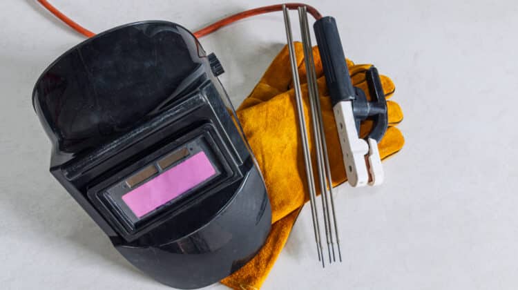 Welding equipment including leather welding gloves welding mask hand held welding electrode on floor