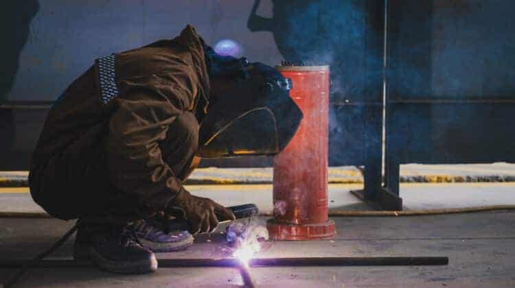 The welder welds metal structures by manual electric arc welding MMA welding