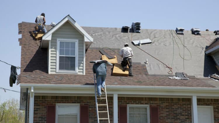 Roofers replacing damaged shingles after storm