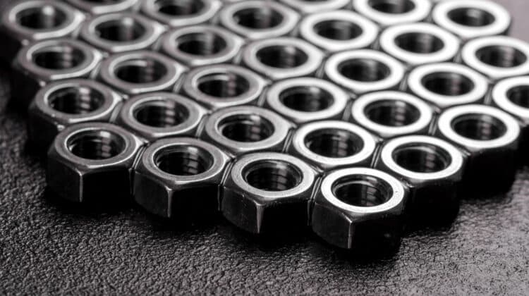 Metal steel nuts laid in composition on a dark table