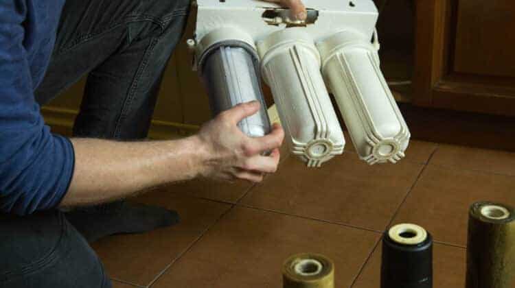Changing filters in your home water purification system The master installs flasks with new filters in the system