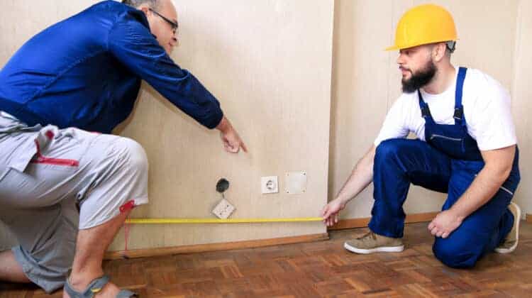 Engineer contractor and project manager with his colleague construction worker handyman and builder is measuring wall room of apartment for renovation using measure tape at construction site