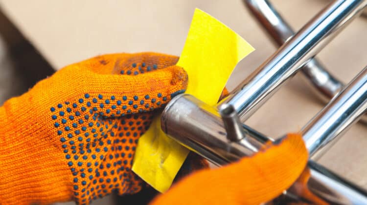 Plumber hand in orange uniform wipes stainless steel surface with a roller Roller grinds metal rail parallel with heated towels