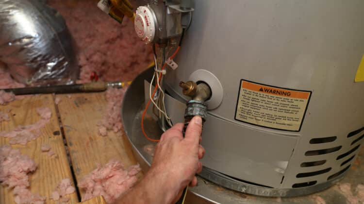 Hand attaches hose to drain water heater