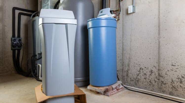Old and new water softener tanks in a utility room waiting for replacement to remove minerals from hard water