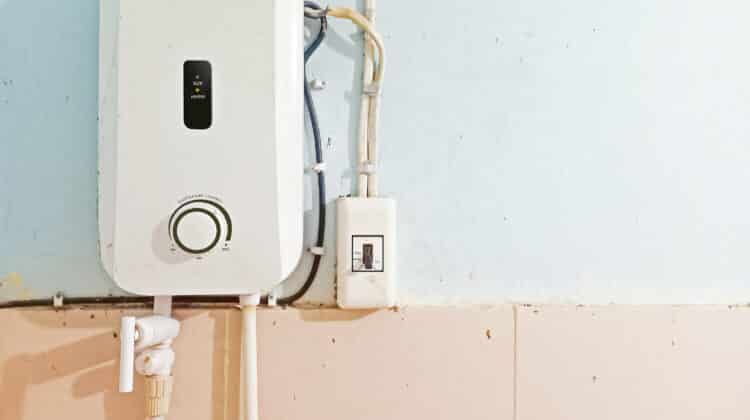 White instant water heater installed with circuit breaker on the wall of bathroom with free copy space
