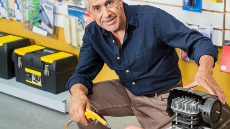 Confident Senior Man With Air Compressor In Store