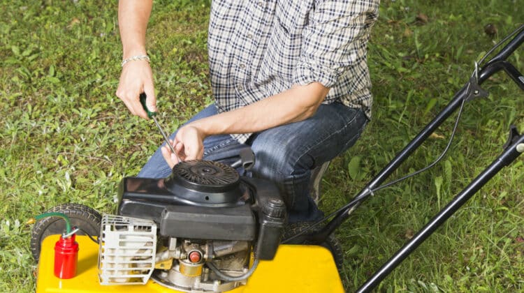 Man repairing yellow lawn mower 