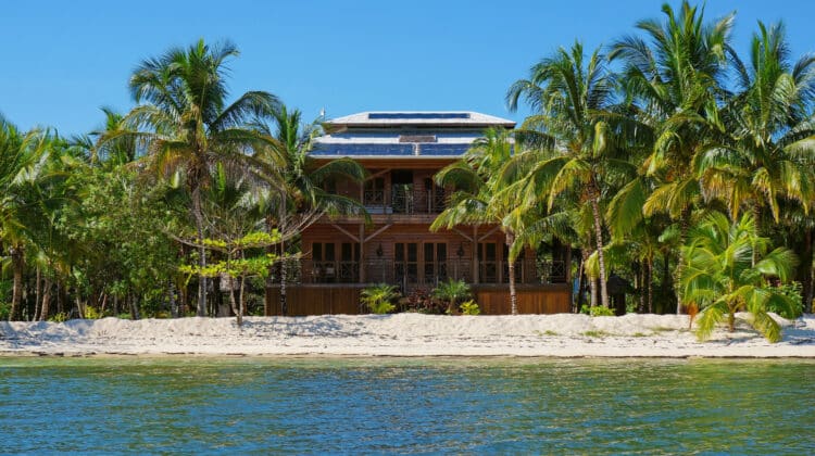 Off-grid beach house with solar panels on the roof and tropical vegetation on an island of the Caribbean sea Panama