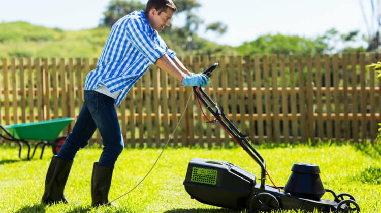 cute man mowing lawn in the backyard of his house