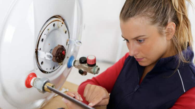 Manual plumber working with electric boiler adjusting power lines installing and cleaning ones