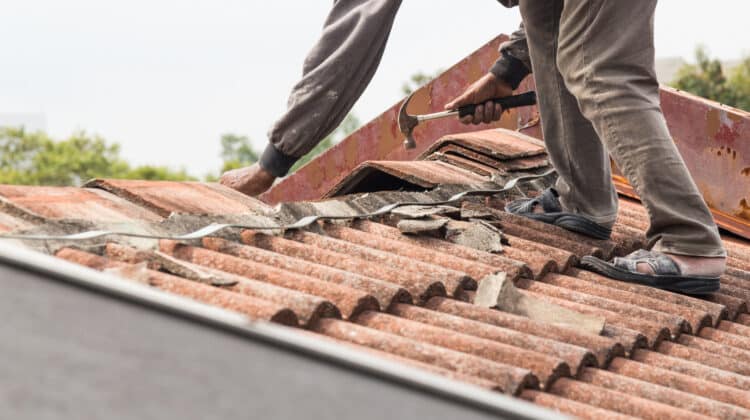 worker replacing roof tiles and metal sheets of old residential building roof