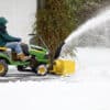 man on riding snow blower clearing snow out of residential driveway