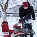 man pours gasoline into snow blower