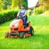 Gardener driving a riding lawn mower in garden