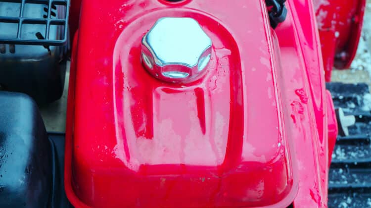 Red gas tank with a metal cap. Fragment of a gasoline snow blower
