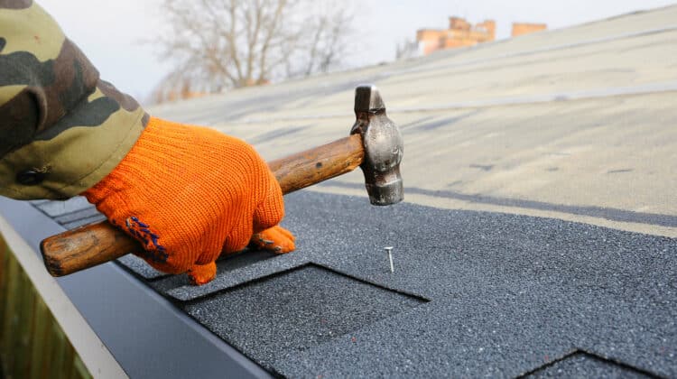 Worker hands installing bitumen roof shingles
