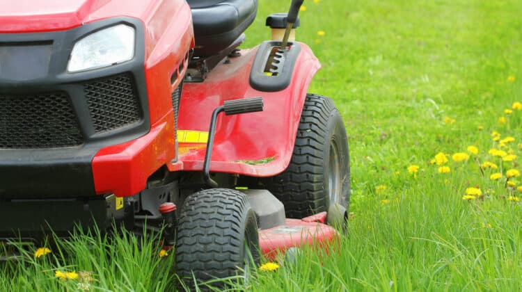 Mowing or cutting the long grass with a lawn mower . Gardening concept background
