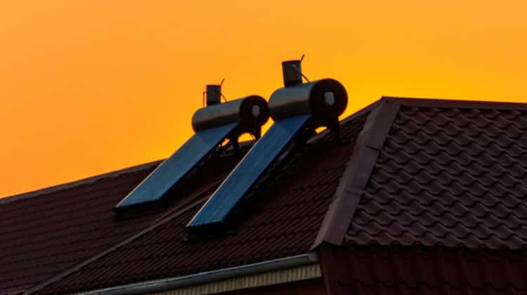 Solar water heaters on a residential house rooftop at sunset