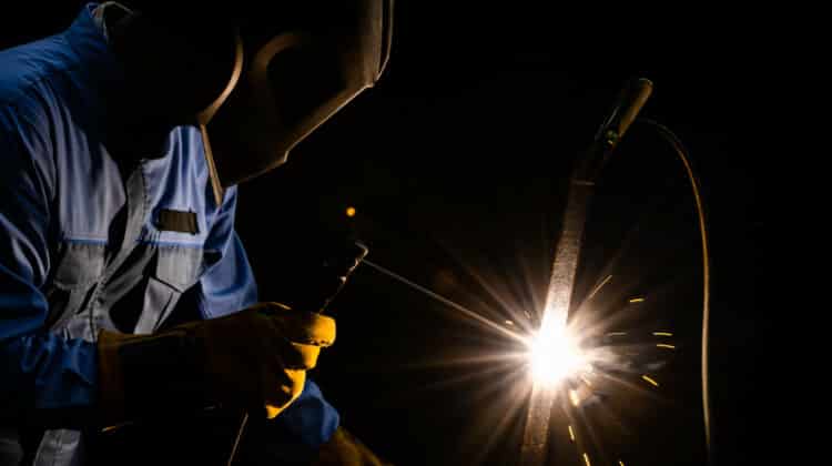 Worker welding metal steel with flux shielded arc welding